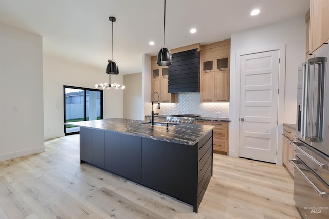 kitchen featuring a kitchen island with sink, stainless steel appliances, light hardwood / wood-style flooring, decorative light fixtures, and decorative backsplash