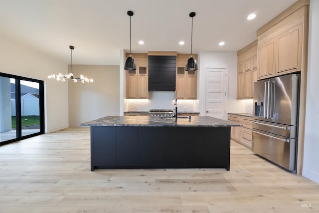 kitchen with high quality fridge, a center island with sink, a chandelier, and light hardwood / wood-style floors