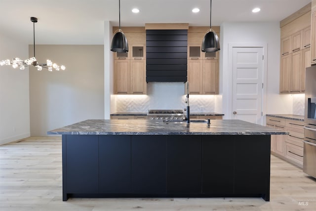 kitchen featuring pendant lighting, light wood-type flooring, an island with sink, and light brown cabinetry