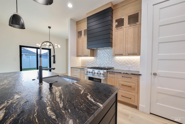 kitchen featuring light brown cabinetry, light wood-type flooring, sink, pendant lighting, and high end stainless steel range