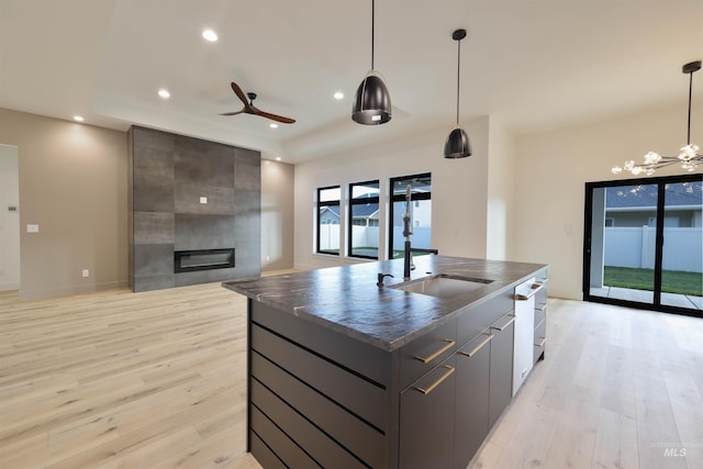 kitchen with pendant lighting, light wood-type flooring, and a kitchen island with sink