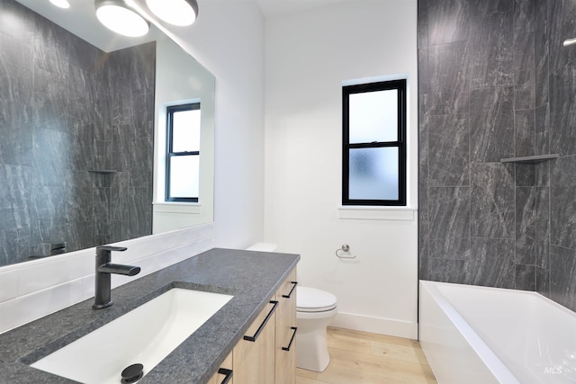 full bathroom featuring tiled shower / bath, hardwood / wood-style floors, vanity, and toilet