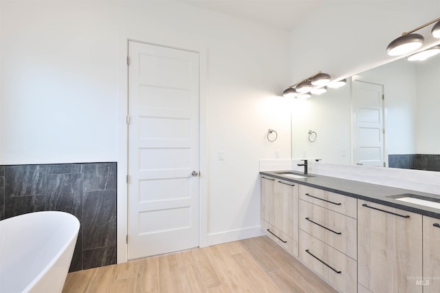 bathroom featuring hardwood / wood-style floors, vanity, a bathing tub, and tile walls