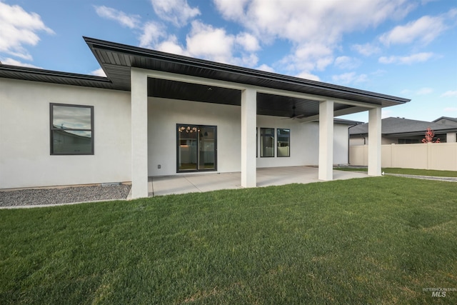 rear view of property featuring a lawn, ceiling fan, and a patio