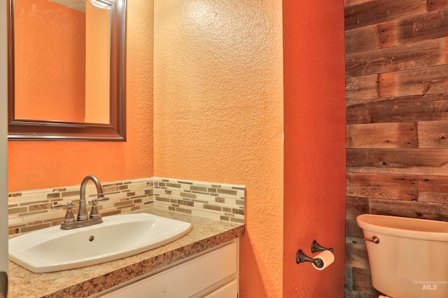 bathroom with tasteful backsplash, toilet, vanity, and a textured wall