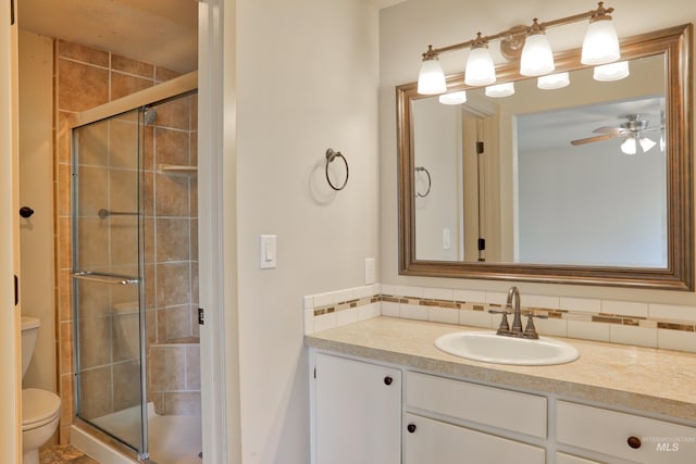 bathroom featuring vanity, ceiling fan, a shower stall, toilet, and backsplash