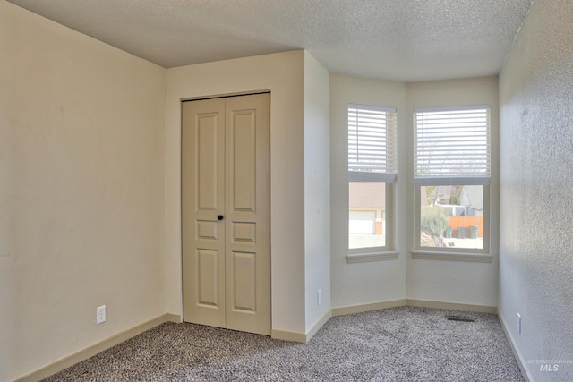 unfurnished bedroom featuring baseboards, visible vents, a textured ceiling, and carpet