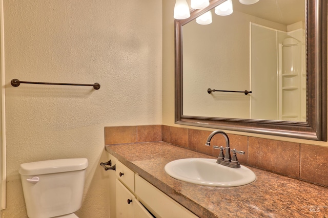 bathroom featuring toilet, vanity, and a textured wall