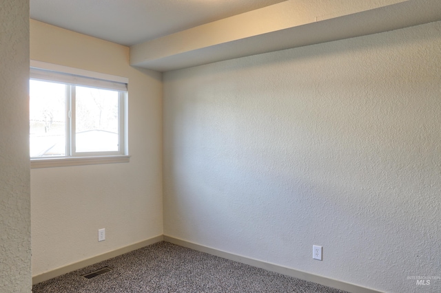 carpeted spare room featuring visible vents and baseboards