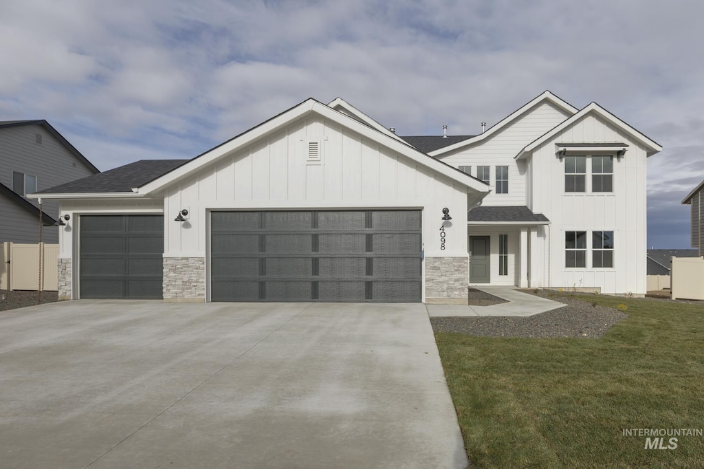 modern farmhouse style home featuring board and batten siding, an attached garage, stone siding, and driveway