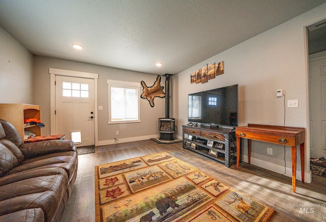 living room featuring a wood stove, wood-type flooring, and a textured ceiling