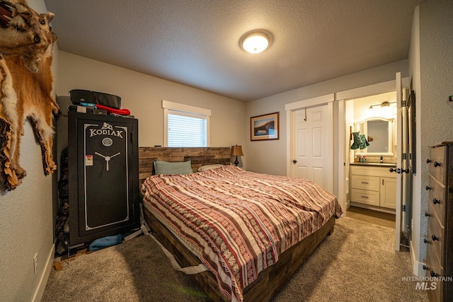 bedroom with ensuite bathroom, light colored carpet, and a textured ceiling