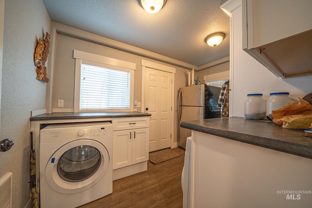 laundry area with cabinets, a textured ceiling, dark hardwood / wood-style flooring, and washer / clothes dryer