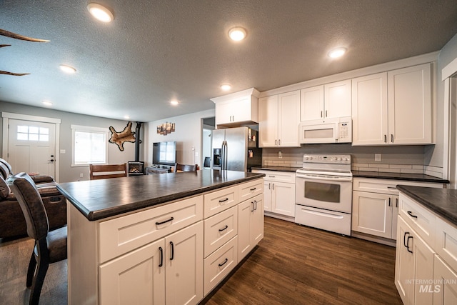 kitchen with white cabinets, dark hardwood / wood-style flooring, white appliances, and a textured ceiling