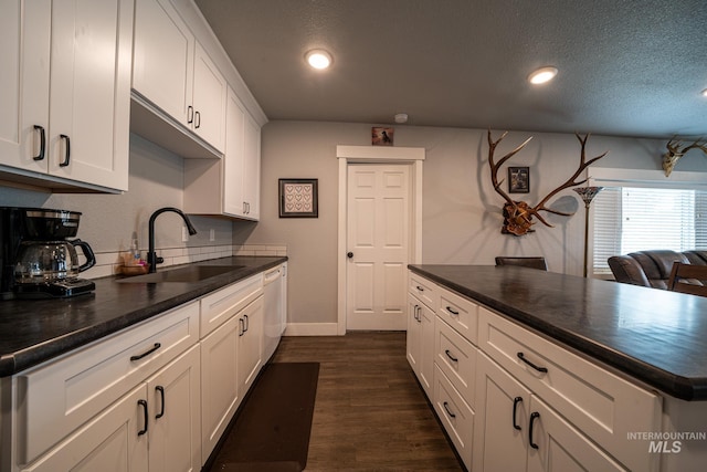 kitchen featuring dishwasher, sink, a textured ceiling, dark hardwood / wood-style flooring, and white cabinetry