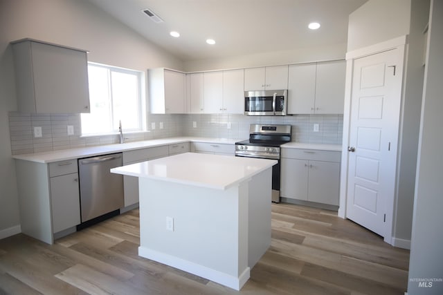 kitchen featuring a kitchen island, lofted ceiling, sink, stainless steel appliances, and light hardwood / wood-style flooring