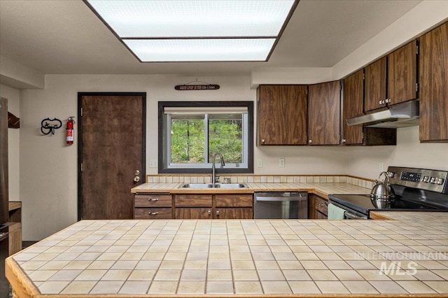 108 Panorama Dr, Cascade, ID 83611 - kitchen featuring appliances with stainless steel finishes, under cabinet range hood, tile countertops, a sink, and dark brown cabinetry