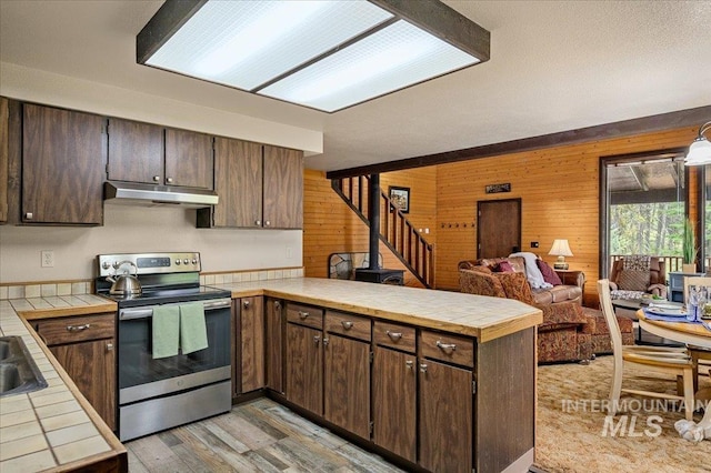 108 Panorama Dr, Cascade, ID 83611 - kitchen with stainless steel electric range oven, under cabinet range hood, a peninsula, tile countertops, and wooden walls