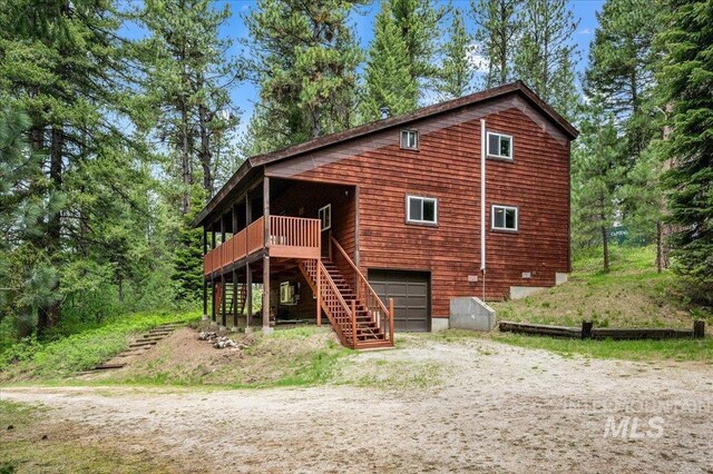 108 Panorama Dr, Cascade, ID 83611 - rear view of house with driveway, an attached garage, stairs, and a deck