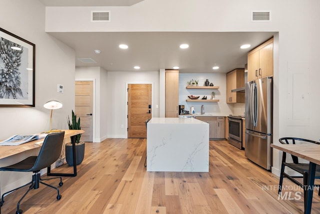 kitchen with appliances with stainless steel finishes, sink, light wood-type flooring, and light brown cabinets