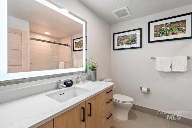 bathroom with vanity, a shower with shower door, tile patterned floors, and toilet