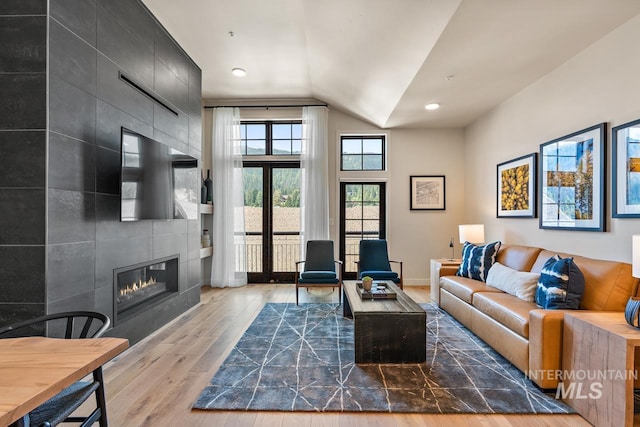 living room featuring lofted ceiling, a fireplace, and hardwood / wood-style floors