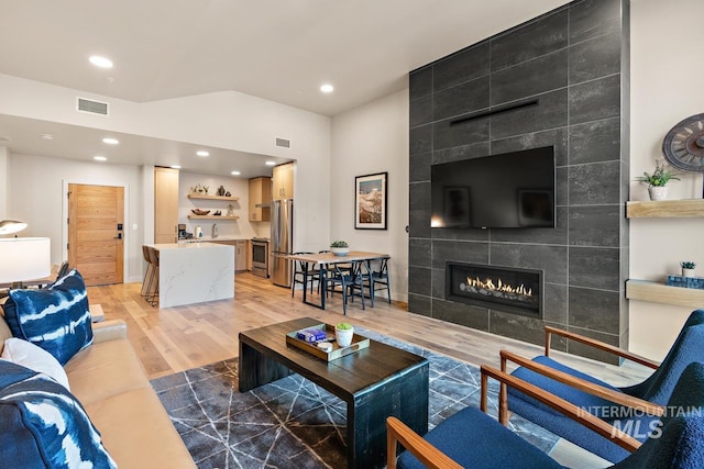 living room with sink, a fireplace, and light hardwood / wood-style floors