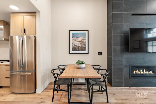 dining room featuring a tiled fireplace and light wood-type flooring