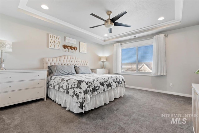 carpeted bedroom with ceiling fan and a raised ceiling