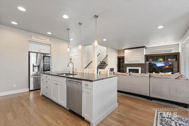 kitchen featuring sink, white cabinets, stainless steel appliances, and a kitchen island with sink