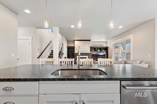 kitchen featuring stainless steel dishwasher, hanging light fixtures, white cabinets, and sink