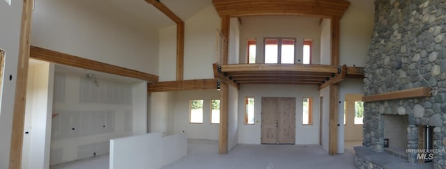 foyer with a high ceiling, light carpet, a fireplace, and plenty of natural light