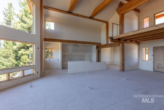 unfurnished living room with beamed ceiling and a high ceiling