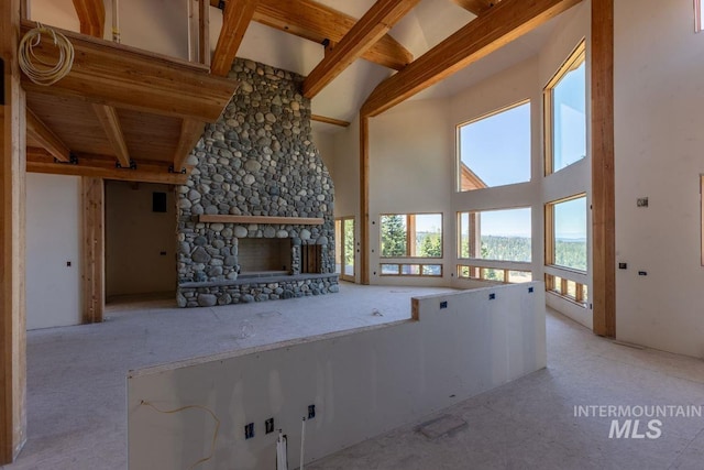 unfurnished living room with a stone fireplace, beam ceiling, and high vaulted ceiling