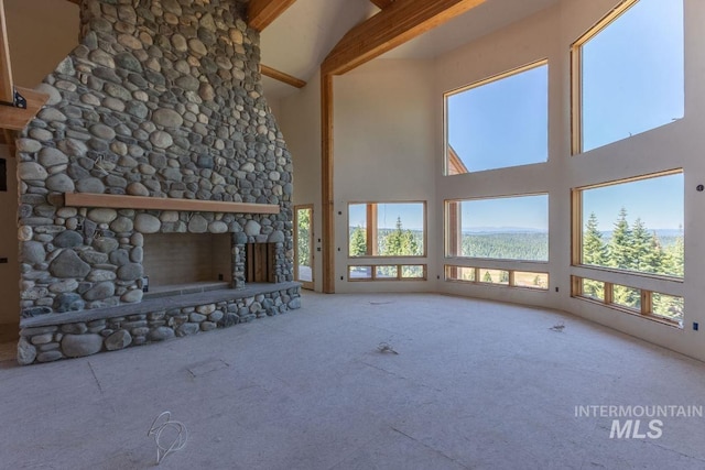 unfurnished living room featuring a healthy amount of sunlight, high vaulted ceiling, and beamed ceiling