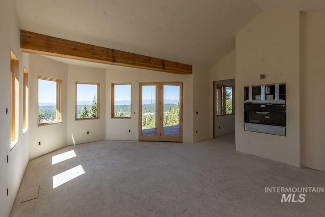 empty room featuring vaulted ceiling with beams and plenty of natural light