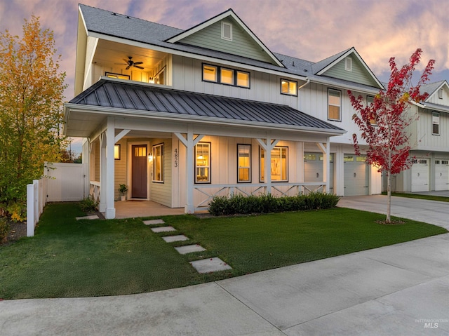 exterior space featuring a garage, a yard, covered porch, and ceiling fan