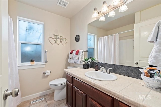 bathroom with tile patterned flooring, vanity, a healthy amount of sunlight, and toilet