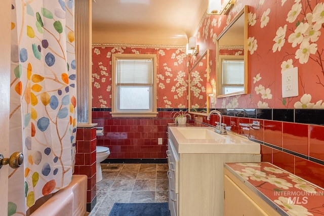 3102 N Sycamore Dr, Boise, ID 83703 - full bathroom featuring wallpapered walls, vanity, wainscoting, toilet, and tile walls
