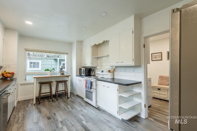 3102 N Sycamore Dr, Boise, ID 83703 - kitchen with stainless steel appliances, dark countertops, open shelves, white cabinets, and wood finished floors