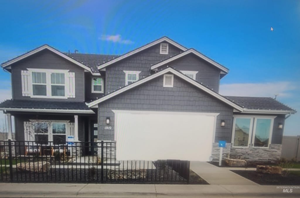 view of front of home featuring stone siding, an attached garage, concrete driveway, and fence