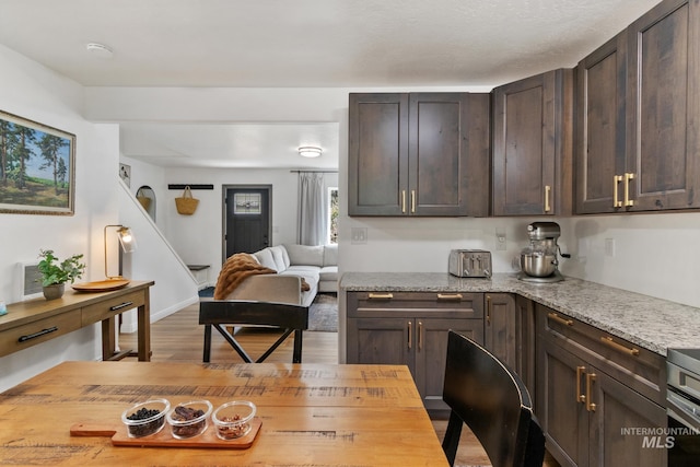 16 Grouse Rd, Idaho City, ID 83631 - kitchen featuring light stone counters, open floor plan, wood finished floors, and dark brown cabinets