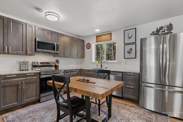 16 Grouse Rd, Idaho City, ID 83631 - kitchen with wood finished floors, dark brown cabinets, a sink, light stone counters, and stainless steel appliances