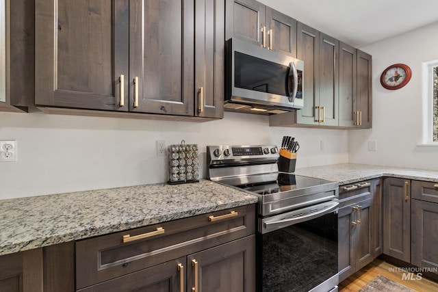 16 Grouse Rd, Idaho City, ID 83631 - kitchen featuring appliances with stainless steel finishes, dark brown cabinetry, light wood-type flooring, and light stone counters