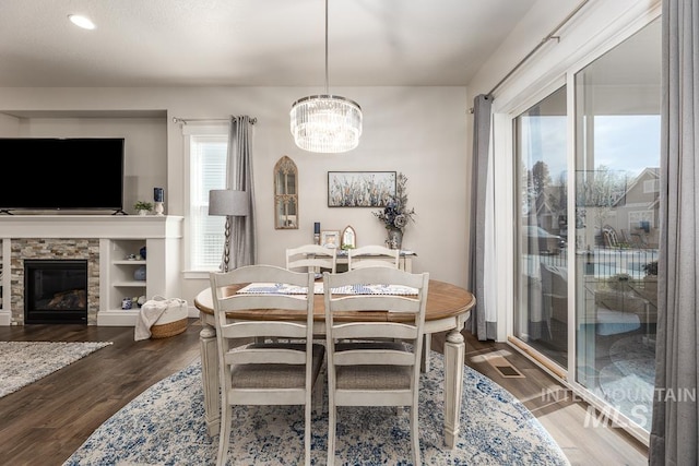 dining room with a chandelier, baseboards, a fireplace, and dark wood-type flooring
