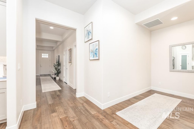 hallway with baseboards, wood finished floors, and visible vents