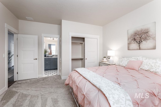 bedroom with ensuite bath, carpet floors, a closet, and baseboards