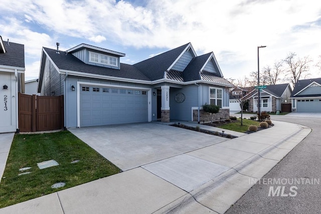 view of front of home featuring a front lawn, driveway, stone siding, fence, and a garage