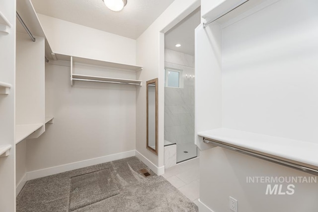 spacious closet featuring visible vents, light carpet, and light tile patterned floors