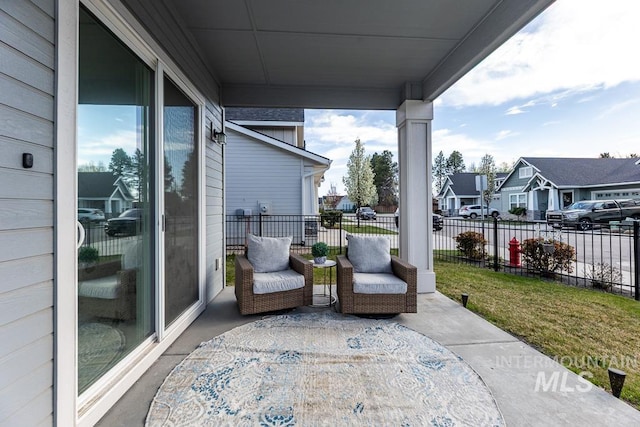 view of patio / terrace with fence, a porch, and a residential view